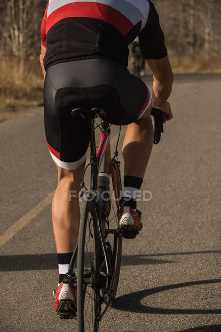 Visão traseira do motociclista andar de bicicleta de montanha na estrada — Fotografia de Stock