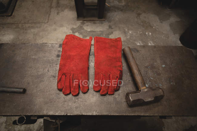 Guanti e martello su superficie metallica in officina — Foto stock