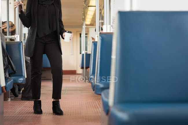 Baixa seção de mulher tomando café enquanto viaja em trem — Fotografia de Stock