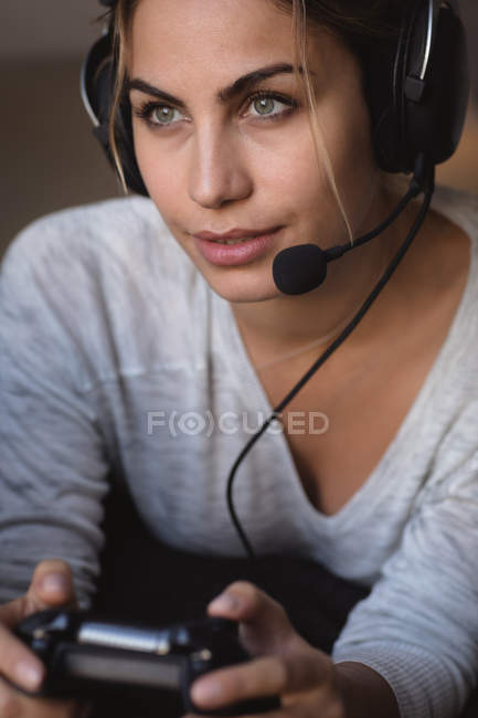 Mulher jogando videogame com fone de ouvido na sala de estar em casa — Fotografia de Stock