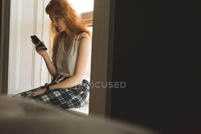 Junge Frau benutzt Handy zu Hause — Stockfoto