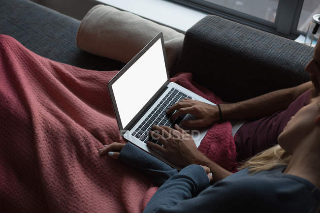 Couple utilisant un ordinateur portable dans le salon à la maison — Photo de stock