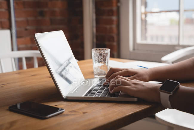 Close-up of female executive using laptop in the creative office — Stock Photo