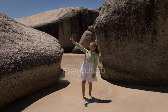 Menina feliz tomando selfie com telefone celular na praia — Fotografia de Stock