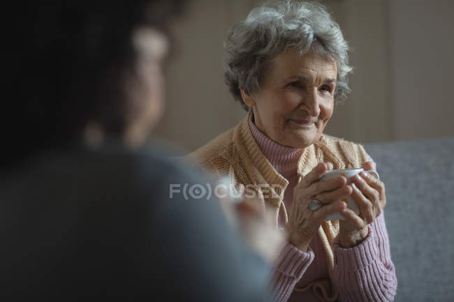 Mother and daughter having coffee in living room at home — Stock Photo