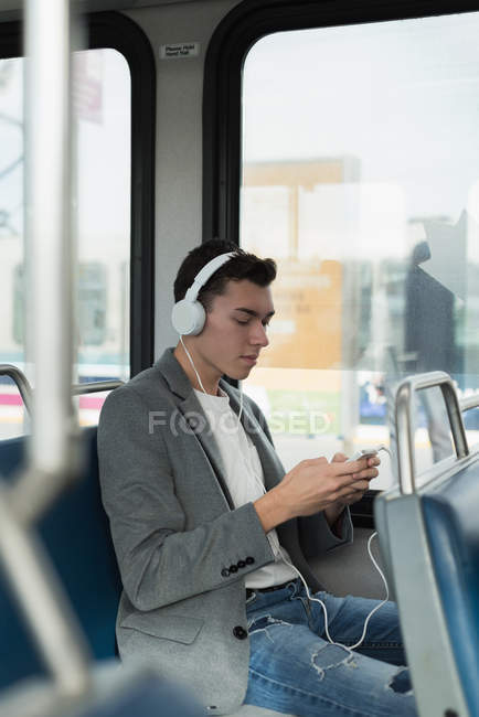 Чоловік слухає музику на навушниках під час подорожі в автобусі — стокове фото