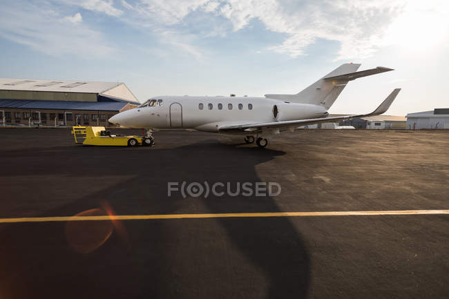 Jet privado con carro en la terminal a la luz del sol - foto de stock