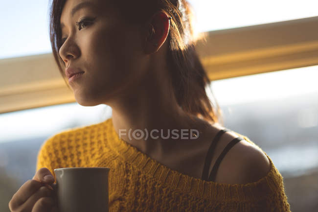 Задумчивая женщина пьет кофе дома — стоковое фото