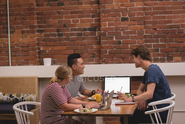 Lächelnde Führungskräfte diskutieren miteinander im Kreativbüro — Stockfoto