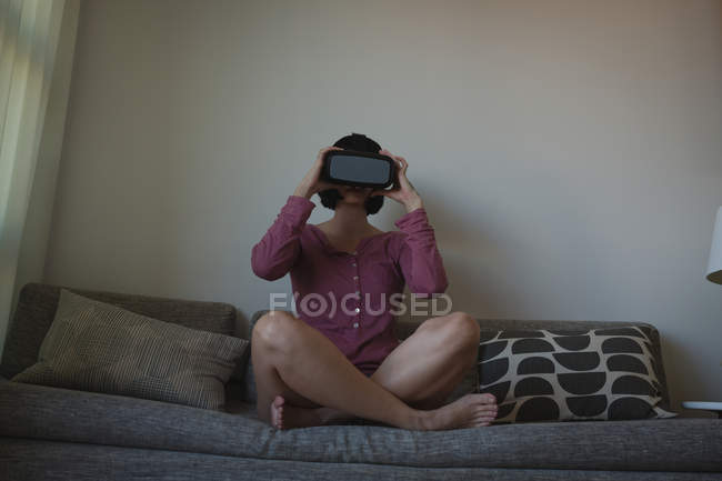 Mujer usando auriculares de realidad virtual en la sala de estar en casa - foto de stock