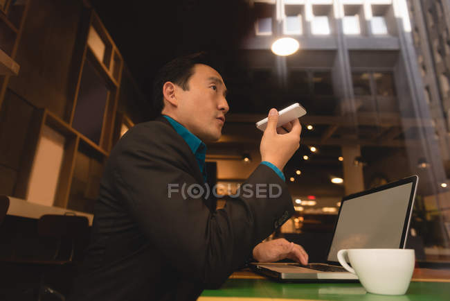 Низкий угол обзора бизнесмена разговаривающего по мобильному телефону в кофейне — стоковое фото