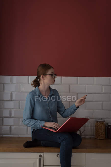 Femme faisant des achats en ligne sur ordinateur portable avec carte de crédit dans la cuisine — Photo de stock
