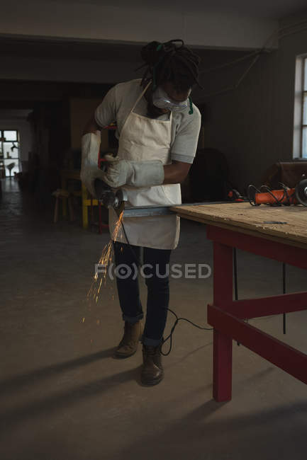 Carpenter cutting metal with electric saw in workshop — Stock Photo
