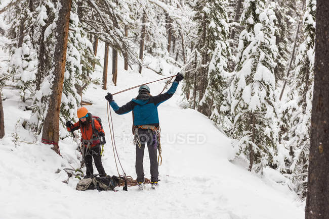Coppia che tiene una corda di sicurezza in montagna innevata durante l'inverno — Foto stock