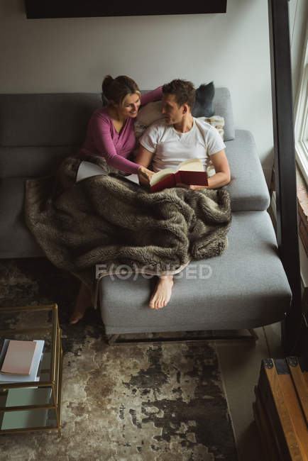 Pareja leyendo libros en la sala de estar en casa - foto de stock