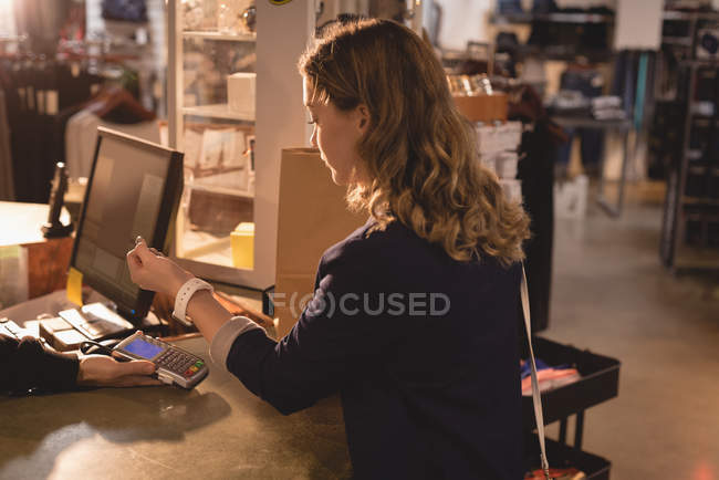 Girl making payment through smartwatch at counter — Stock Photo