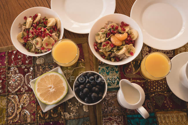 Vista de alto ángulo del desayuno y el jugo en la mesa en casa . - foto de stock