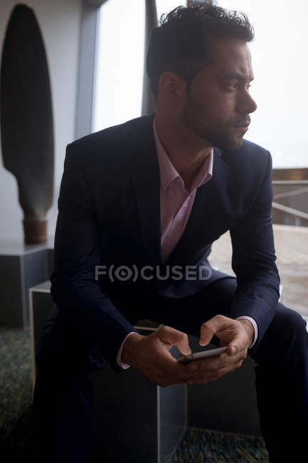Thoughtful Businessman using mobile phone in hotel room — Stock Photo