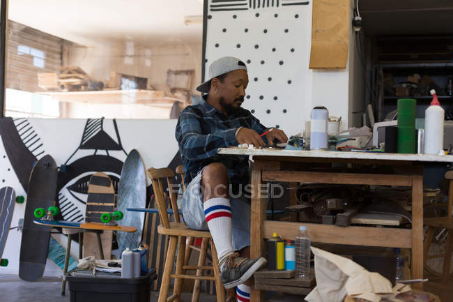 Mann bastelt in Skateboard-Werkstatt Design auf Papier — Stockfoto