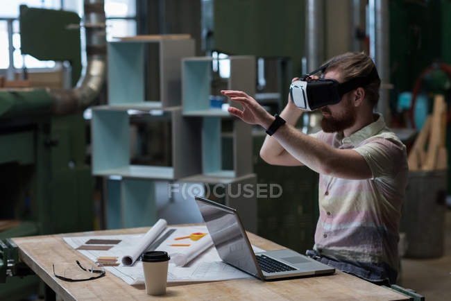 Carpinteiro masculino usando fone de ouvido de realidade virtual na oficina — Fotografia de Stock