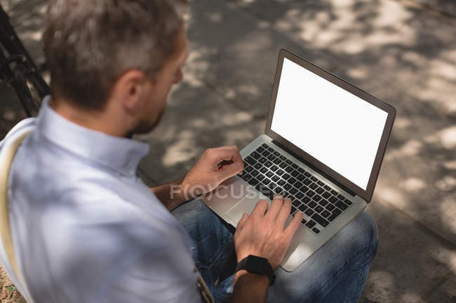 Людина, використовуючи ноутбук у парку сонячний день — стокове фото