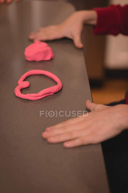 Garçon préparant la forme du cœur avec une argile à la maison — Photo de stock