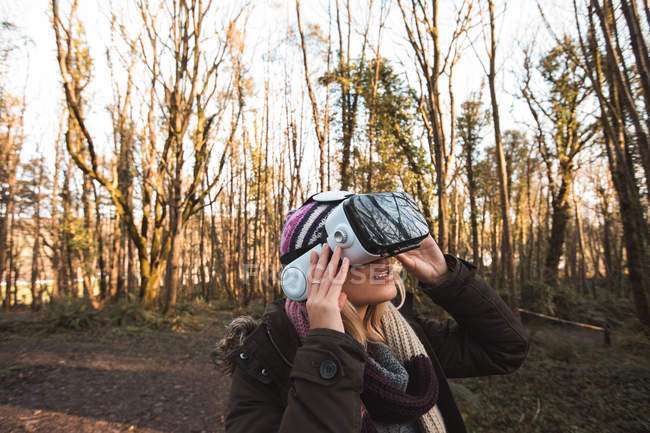 Жінка використовує гарнітуру віртуальної реальності в лісі в сонячний день — стокове фото