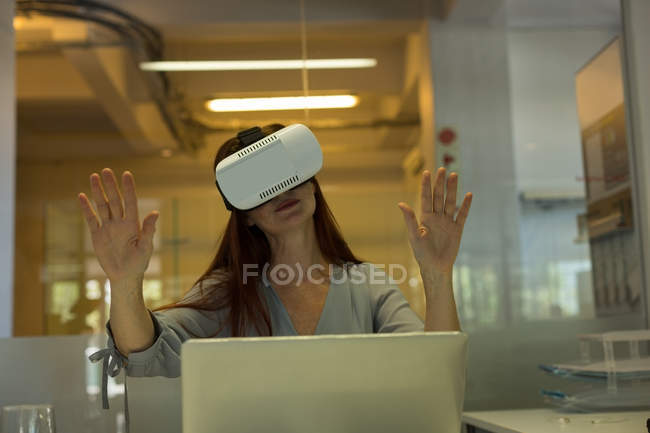 Executivo feminino usando fone de ouvido de realidade virtual no escritório — Fotografia de Stock