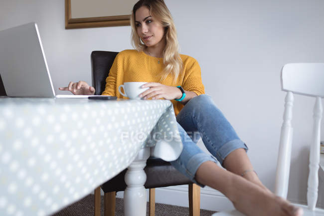Frau benutzt Laptop auf Esstisch zu Hause — Stockfoto