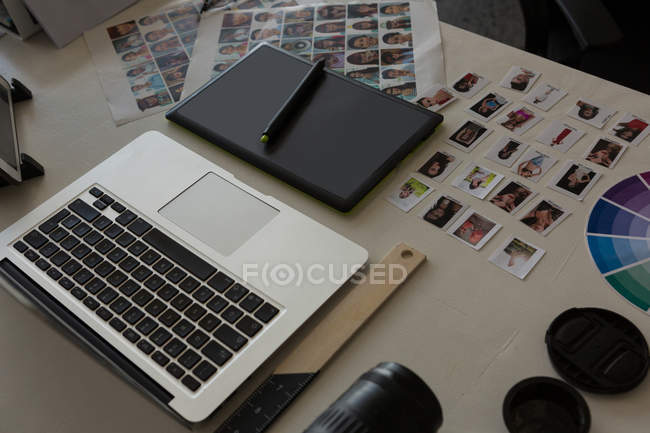 Ordenador portátil con tableta gráfica, lápiz óptico y fotos en el escritorio en la oficina - foto de stock