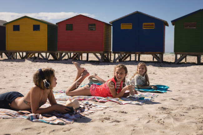 Счастливые братья и сестры общаются во время отдыха на пляже в солнечный день — стоковое фото