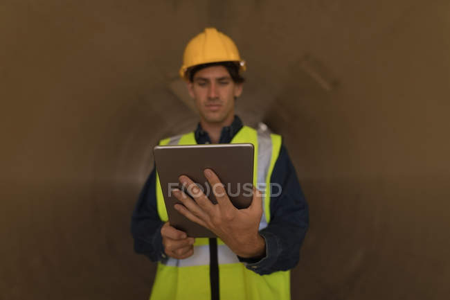 Aufmerksame männliche Arbeiter mit digitalem Tablet in einem Betontunnel — Stockfoto