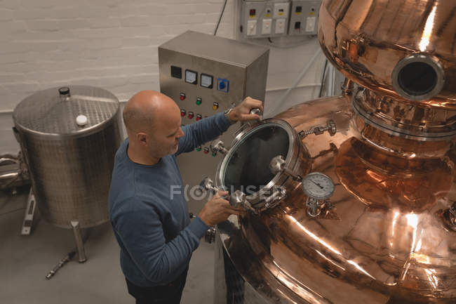 Чоловічий працівник перевіряє машину винокурні на заводі — стокове фото
