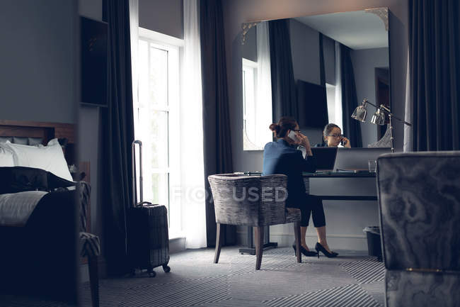 Женщина разговаривает по мобильному телефону за столом в отеле — стоковое фото