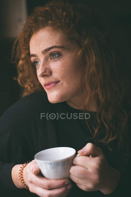 Mulher atenciosa tomando xícara de café em casa — Fotografia de Stock