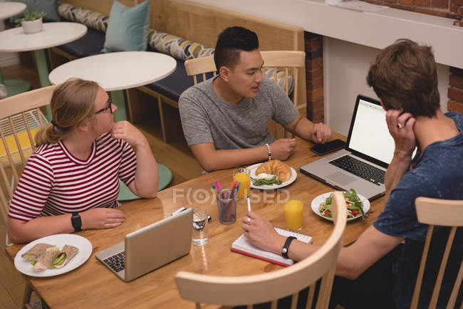 Виконавці обговорюють ноутбук один з одним в кафетерії в творчому офісі — стокове фото