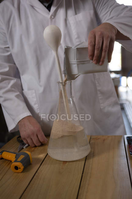 Sección media del trabajador masculino experimentando ginebra en fábrica - foto de stock