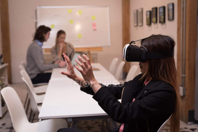 Female executive using virtual reality headset in office interior. — Stock Photo