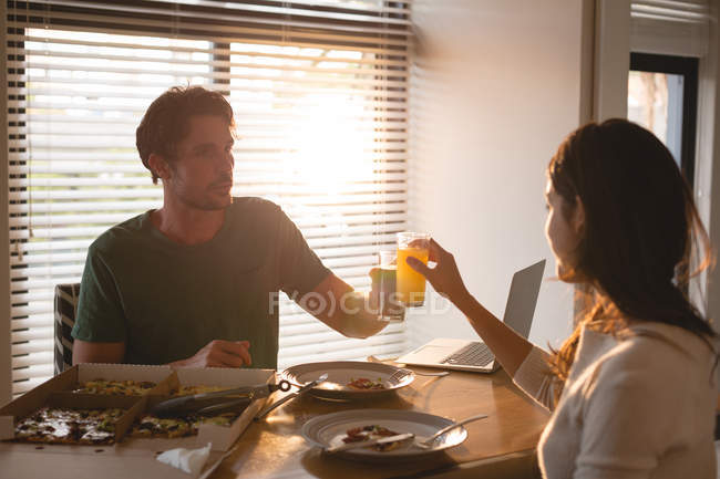 Couple toasting verres de jus à la maison — Photo de stock