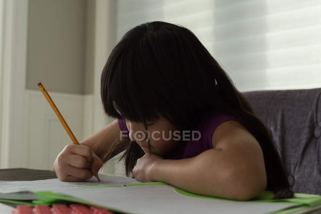 Очаровательная девушка делает домашнее задание дома — стоковое фото