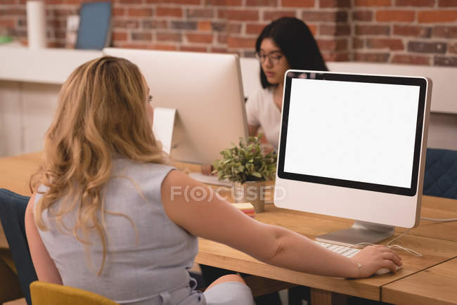 Ejecutivas que trabajan en la computadora en la oficina creativa - foto de stock