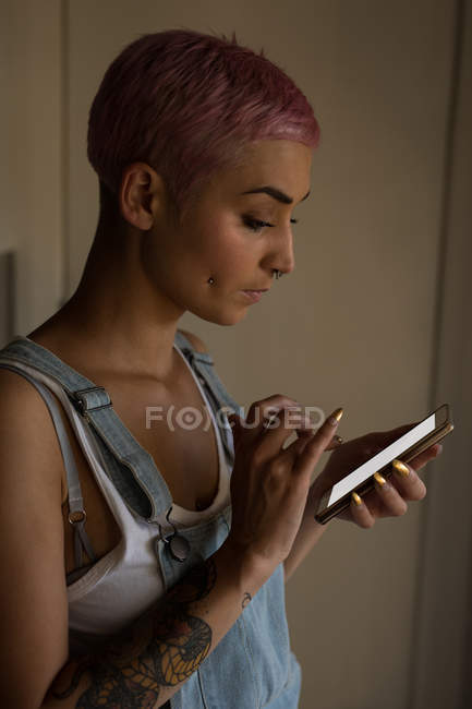 Junge Frau mit rosafarbenen Haaren benutzt Handy im Haus. — Stockfoto
