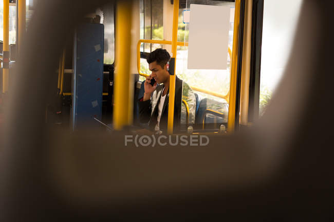 Joven hombre de negocios tomando el teléfono móvil mientras viaja en autobús - foto de stock
