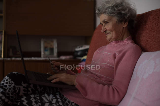 Mulher idosa ativa usando laptop em casa — Fotografia de Stock