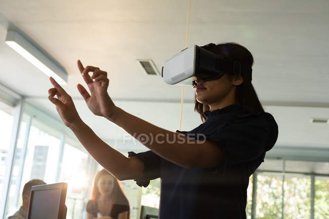 Женщина-руководитель, использующая гарнитуру виртуальной реальности в офисе — стоковое фото