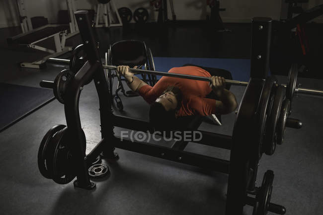 Hombre discapacitado haciendo ejercicio en el pecho en press de banca con barra en el gimnasio - foto de stock