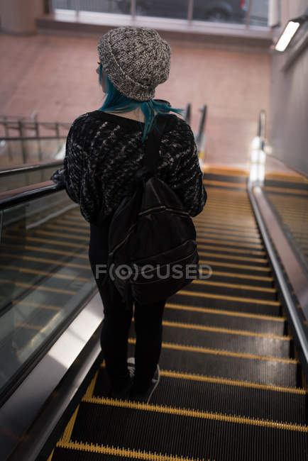 Vue arrière d'une femme descendant d'un escalier roulant à la gare — Photo de stock
