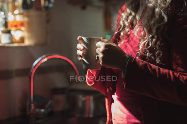 Seção média de mulher madura tomando café em casa — Fotografia de Stock