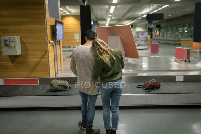 Вид сзади на пару, обнимающую друг друга в аэропорту — стоковое фото