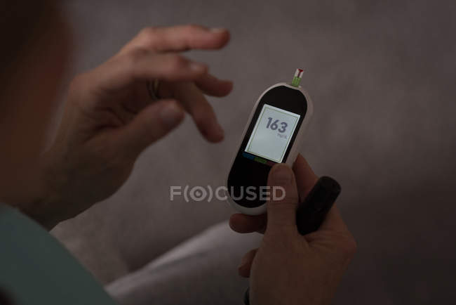 Seniorin überprüft Blutdruck zu Hause auf Monitor — Stockfoto